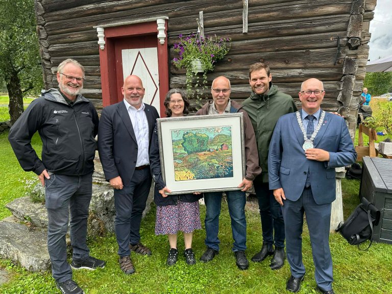 Oppstilling foran brunt stabbur. Knut Flatvad og Rita Dyrnes Flatvad, Østigard Flatvad i Sunndal, Møre og Romsdal mottok den nasjonale kulturlandskapsprisen i 2025 for arbeidet med å ta vare på verdier i jordbrukets kulturlandskap i Sunndal.