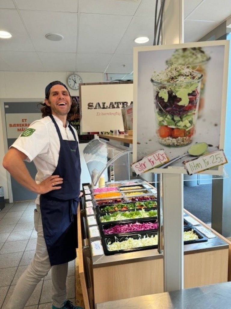 Salatbar med mye farger og en smilende kantinemann.