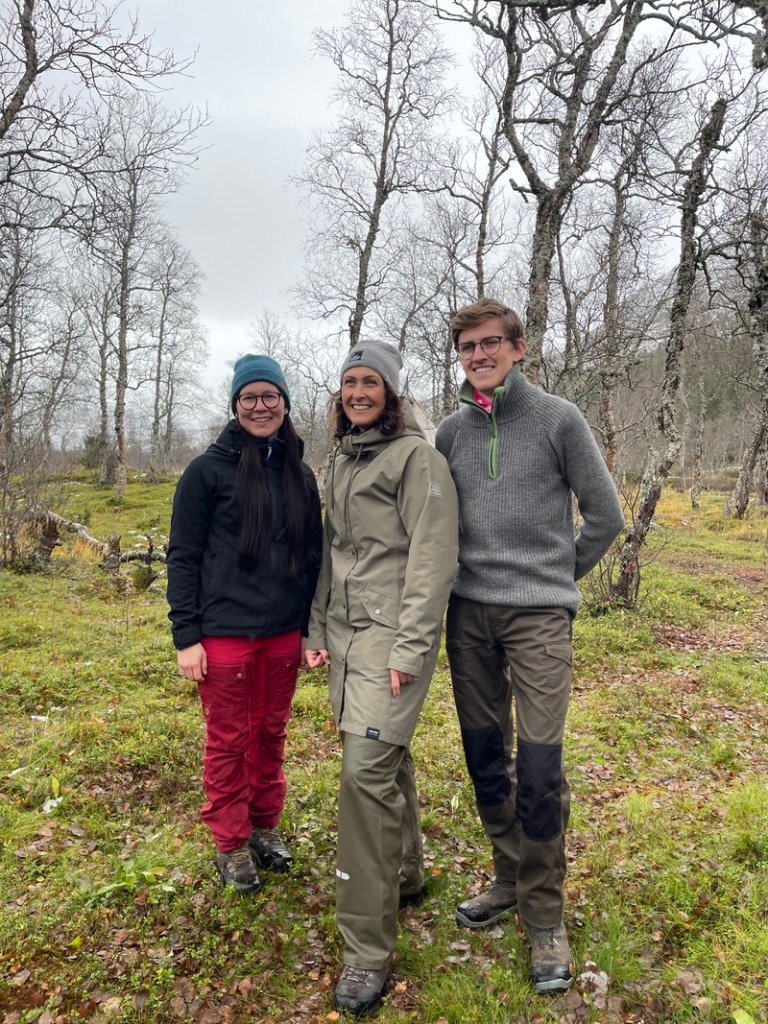 Bilde i skogen av Ellen-Sara Sparrok Larsen som er leder i Norske Reindriftsamers Landsforbunds ungdomsutvalg, i midten statssekretær Wenche Westberg og Henrik Nordtun Gjertsen som var styreleder i NBU.   Foto: Landbruksdirektoratet
